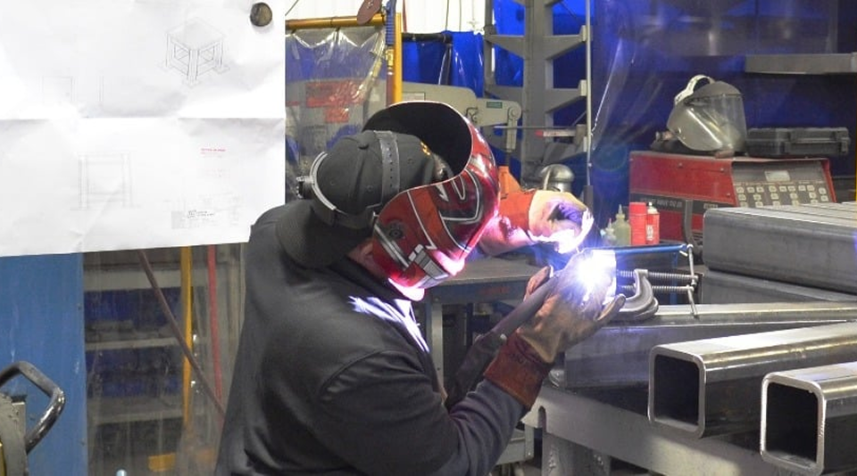 person with a face shield working in a fabrication factory